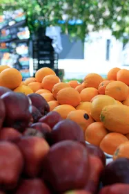 Display of fresh oranges and red apples at an outdoor market stand.